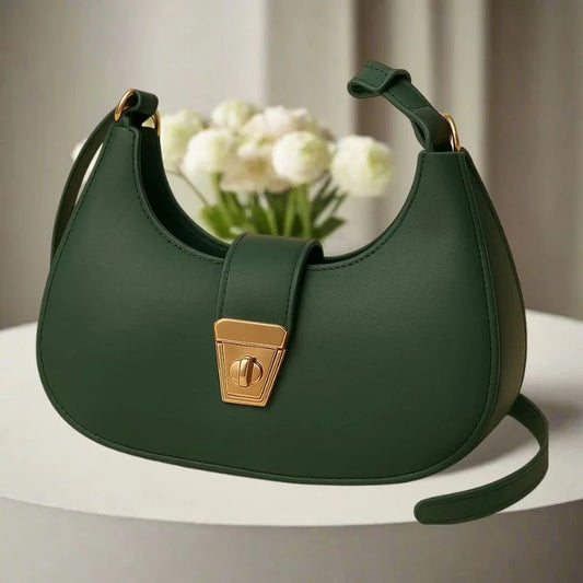 Green handbag with a gold clasp on a white surface with a blurred background