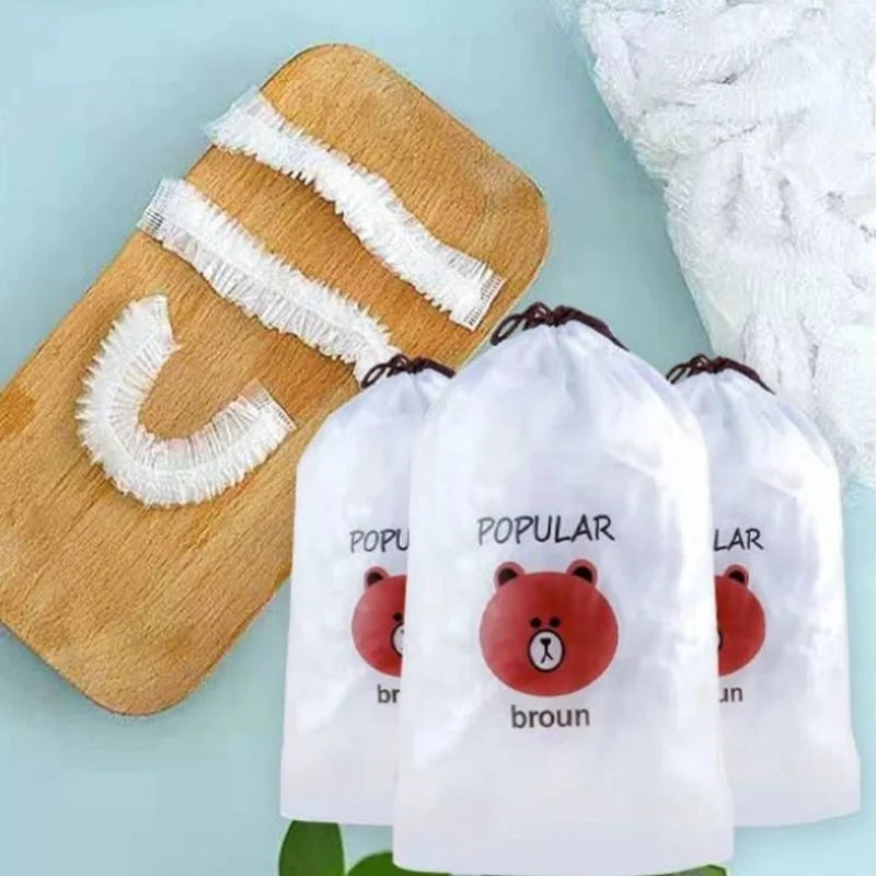 Three white drawstring pouches with a red cartoon bear face and the word 'broun' printed on them, arranged in front of a wooden scrubber with white fringed scrubbing pads on a light blue background.