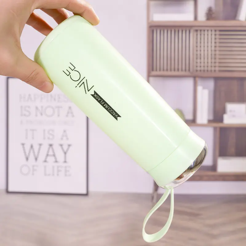 Hunt PK Light green water bottle with a strap held by a hand in an indoor setting.
