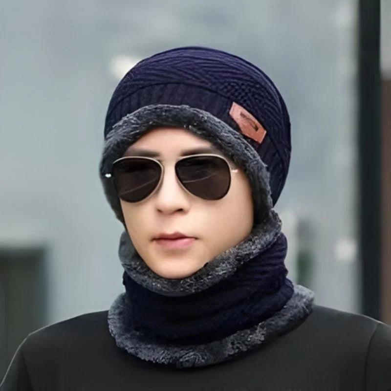 Hunt PK Person wearing a dark blue knit beanie and scarf with sunglasses, against a blurred background.